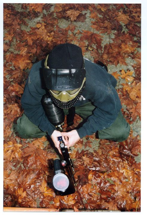 Paintball player photographed in action at a bunker.
